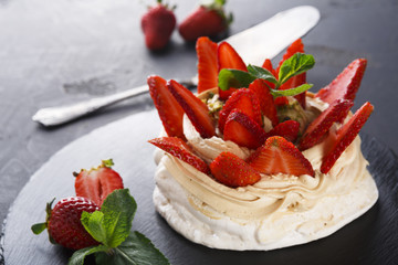 Delicious Anna Pavlova meringue cake with strawberry on black background