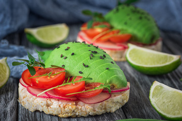 Bruschetta with tomato, avocado, herbs and arugula. Rustic background. Top view