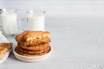 Fresh healthy milk and oatmeal cookies with cereals on grey concrete background. Copy space
