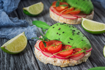 Bruschetta with tomato, avocado, herbs and arugula. Rustic background. Top view