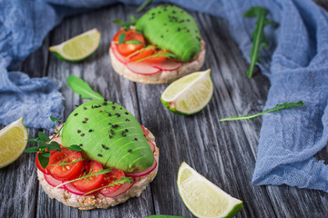 Bruschetta with tomato, avocado, herbs and arugula. Rustic background. Top view