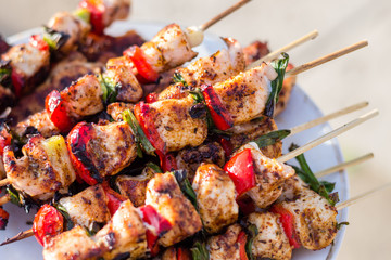 Close up pf delicious chicken breast on wooden skew with fresh vegetables, garlic, paprika fried on mangal barbeque grill