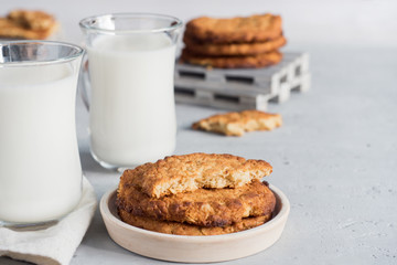 Fresh healthy milk and oatmeal cookies with cereals on grey concrete background