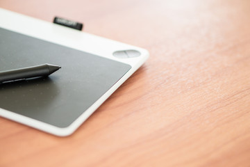 Stylus pen and pad is on the wooden desk.
