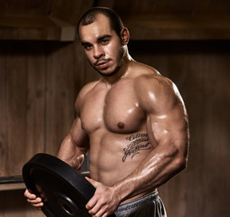 Fototapeta na wymiar Portrait of handsome muscular athlete holding plate for weightlifting