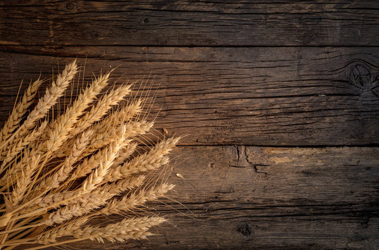 Wheat ears on rustic wooden background.