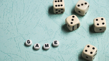 The word "Game" is composed of multicolored wooden letters and game dice on a mint background.