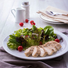 Grilled chicken breast salad with tomatoes and lettuce salad on a white plate