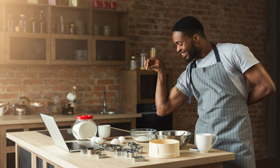 Fototapeta na wymiar African-american man baking cookies at home kitchen