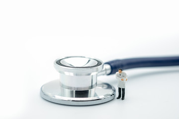 Health Care concept. Doctor miniature figure standing with stethoscope on white background.