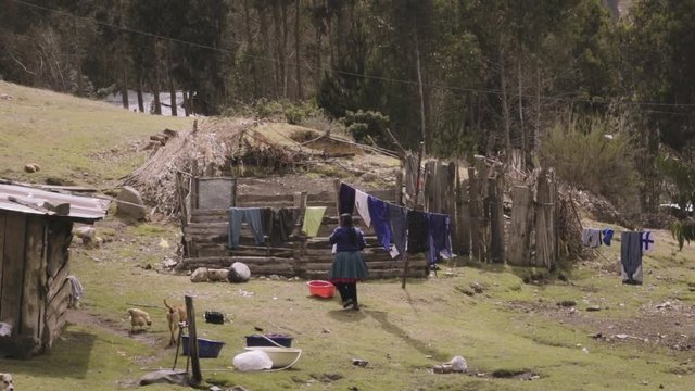Indigenous woman working around the wood barnyard in a small settlement of the andes mountains. Slow motion