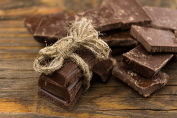 Pieces of chocolate, cinnamon and star anise on a wooden table.