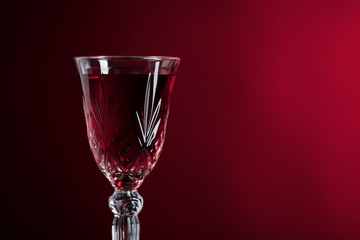 Close-up of crystal glass with red wine on dark background.