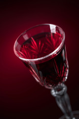 Close-up of crystal glass with red wine on dark background.