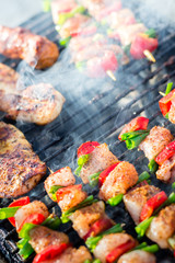 Close up pf delicious chicken breast on wooden skew with fresh vegetables, garlic, paprika fried on mangal barbeque grill