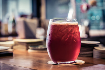 Red beverage on a wooden table in a restaurant. (vintage tone)