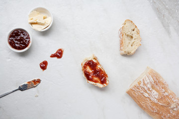 Flat lay of homemade french bread baguette sliced with strawberry jam and butter 