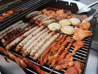 Various assorted meat on a grill. Grilling season concept. Sausages, meat rolls, grilled tofu. Delicious eating. Top view, close up