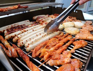 Various assorted meat on a grill. Grilling season concept. Sausages, meat rolls, grilled tofu. Delicious eating. Top view, close up