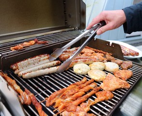 Various assorted meat on a grill. Grilling season concept. Sausages, meat rolls, grilled tofu. Delicious eating. Top view, close up