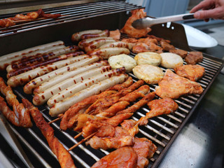 Various assorted meat on a grill. Grilling season concept. Sausages, meat rolls, grilled tofu. Delicious eating. Top view, close up