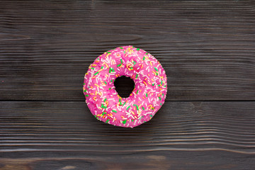 Pink donut on brown wooden background. Top view. Close-up