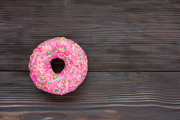 Pink donut on brown wooden background. Top view. Copy space for text, logo and design