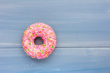Pink donut on blue wooden background. Top view. Copy space for text, logo and design