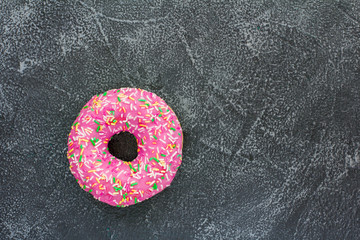Pink donut on gray stone background. Top view. Copy space for text, logo and design