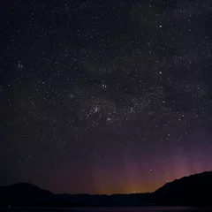 Foto auf Acrylglas Night picture of a minimal landscape of the stars and Southern Cross in New Zealand. The purple, yellow, red and orange lights emerging behind the mountains came from Queenstown. © josemanuelerre