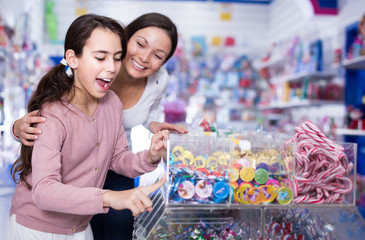 Woman and daughter with open mouth buying sweet candies