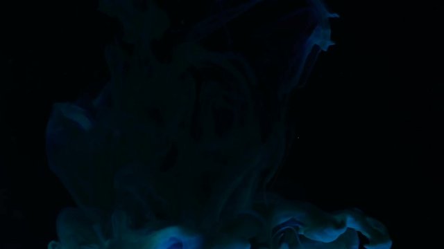 This is a creative artistic macro video of colorful blue abstract shape dropping into black water