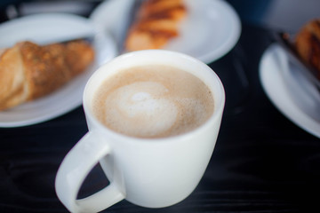 Cup of double espresso coffee with piece of cake on wooden table