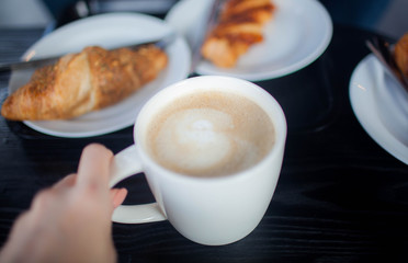 Cup of double espresso coffee with piece of cake on wooden table