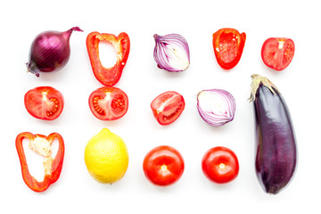 Layout of contrast, colored vegetables. Eggplant, red onion, red pepper, tomato on white background top view pattern