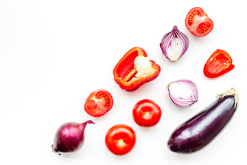 Layout of contrast, colored vegetables. Eggplant, red onion, red pepper, tomato on white background top view copy space pattern