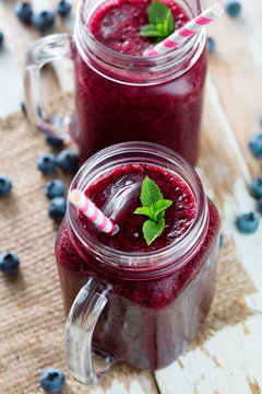 Berry smoothie in glass with blueberries, mint and cocktail tube