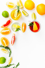 Concept of alcoholic cocktail with fruits. Glass with beverage near oranges, grapefruit, lime and rosemary on white background top view copy space