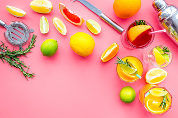 Bartender workplace for make fruit cocktail with alcohol. Shaker, strainer and other bar tools near citrus fruits and glass with cocktail on pink background top view copy space