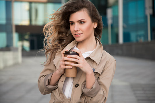 Keep on walking! Closeup picture of good-looking graceful young girl holding her tasty coffee-to-go and dreaming about pleasantness.