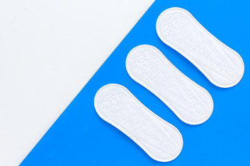 Women's hygiene products. Critical days concept. Sanitary pads on blue background top view copy space pattern