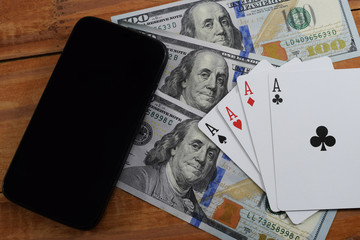 Fototapeta na wymiar virtual casinos, real money. cell phone, dollar and playing cards