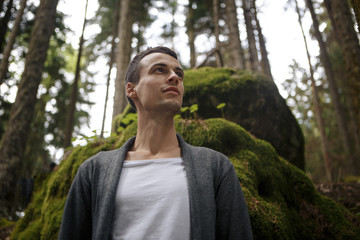 Portrait of young male backpacker with a rucksack standing on the mountain hill while enjoying nature scenery view with plants copy space area background for your text message or advertising content