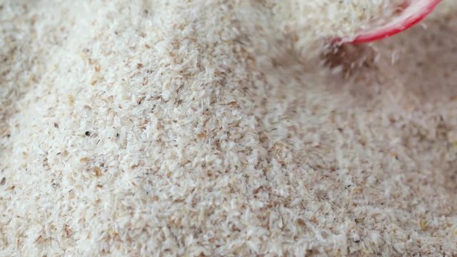 A very close slow motion video of using a red spoon to stir dry psyllium husks then take a spoonful at the end.