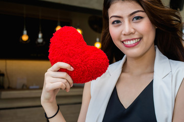 Beautiful woman holding a red heart in her hand..