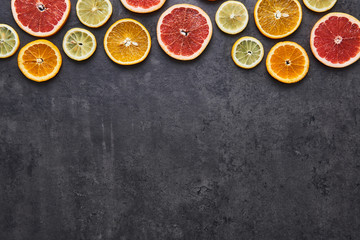 Flat lay of citrus fruits pattern of lemon, orange and grapefruit on black stone background. Copy space at the bottom. Top view.