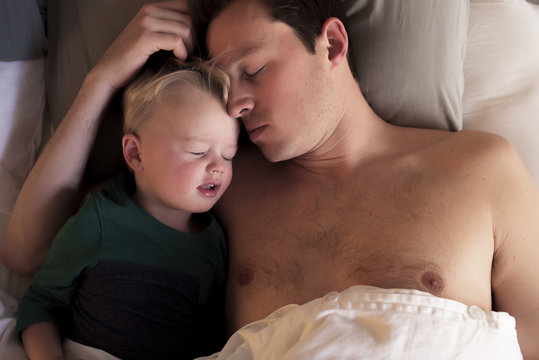 High angle view of father with son sleeping on bed at home