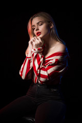 Magnificent blonde girl with red lips posing with closed eyes at studio