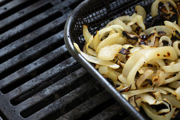 Close up on grilled onions in a grilling basket on a barbecue grill