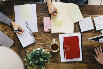 Overhead view of businesswomen writing on papers at desk in office